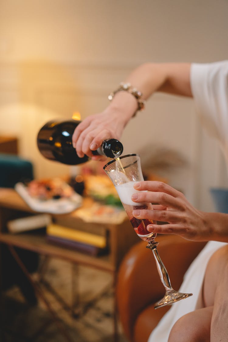 Close-up Of Woman Pouring Champagne Into A Glass 