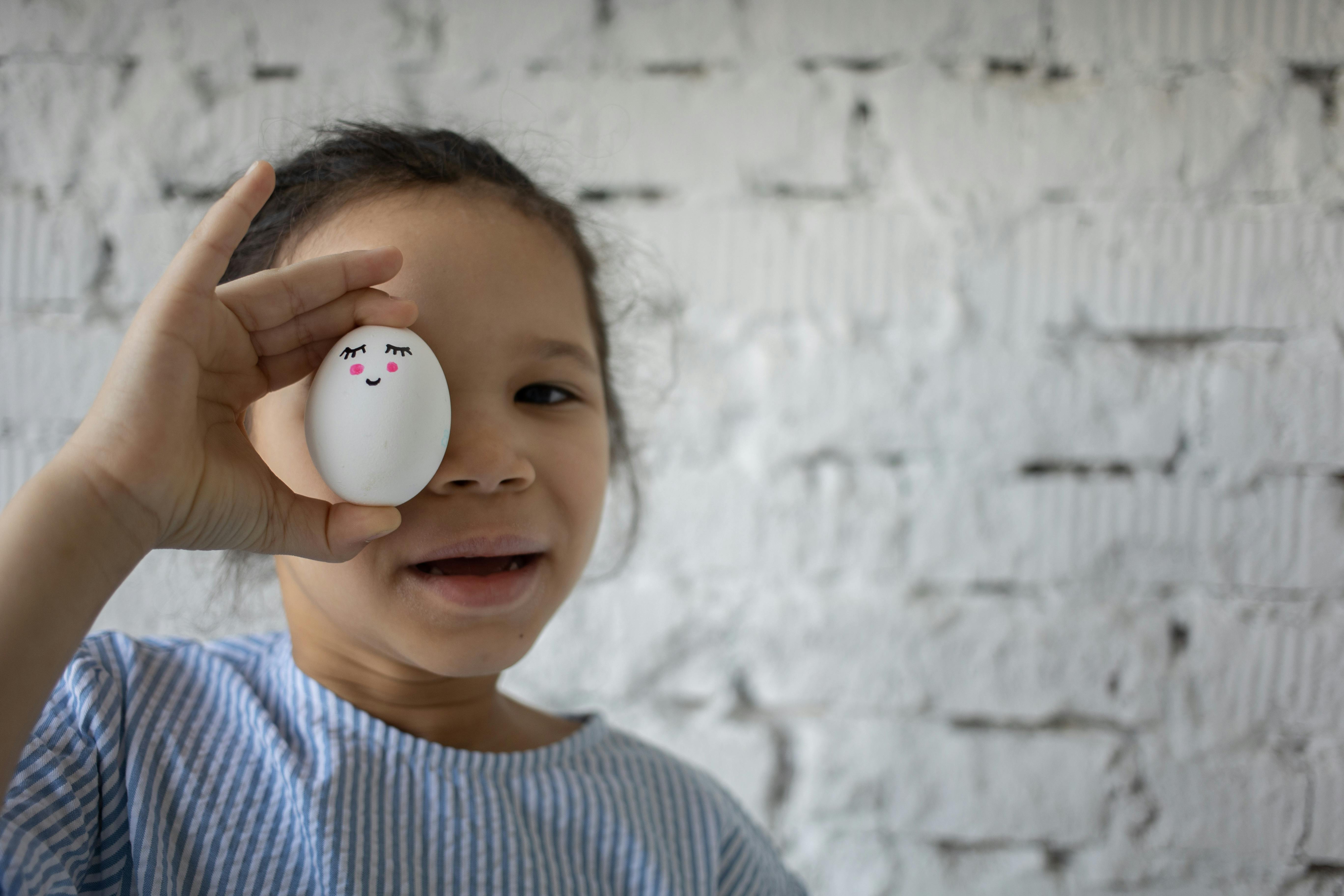 Girl Holding White Egg with Face · Free Stock Photo