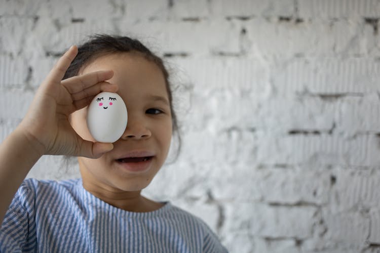 Girl Holding White Egg With Face