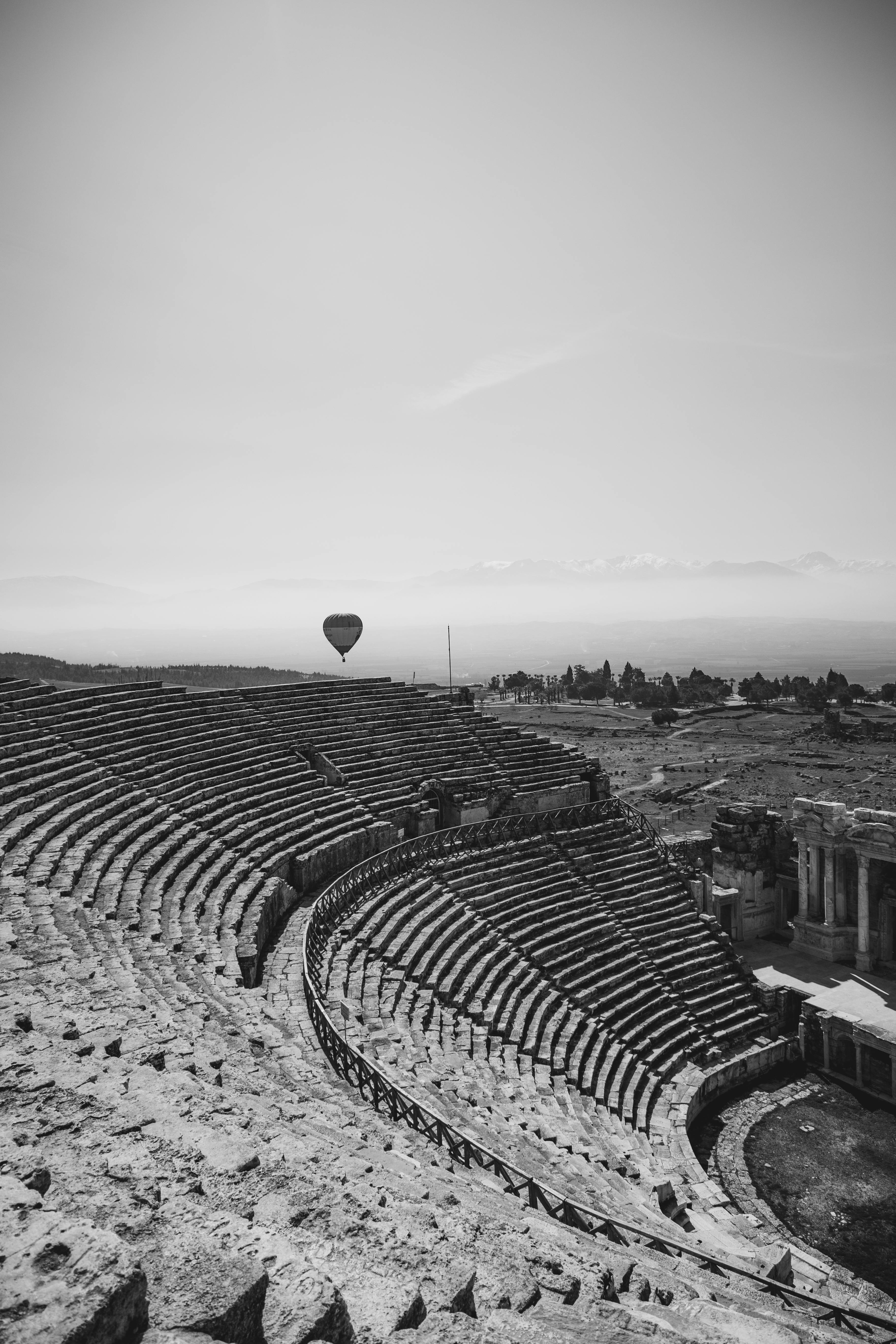Free Black and white photo of a hot air balloon above an ancient Roman theatre. Stock Photo
