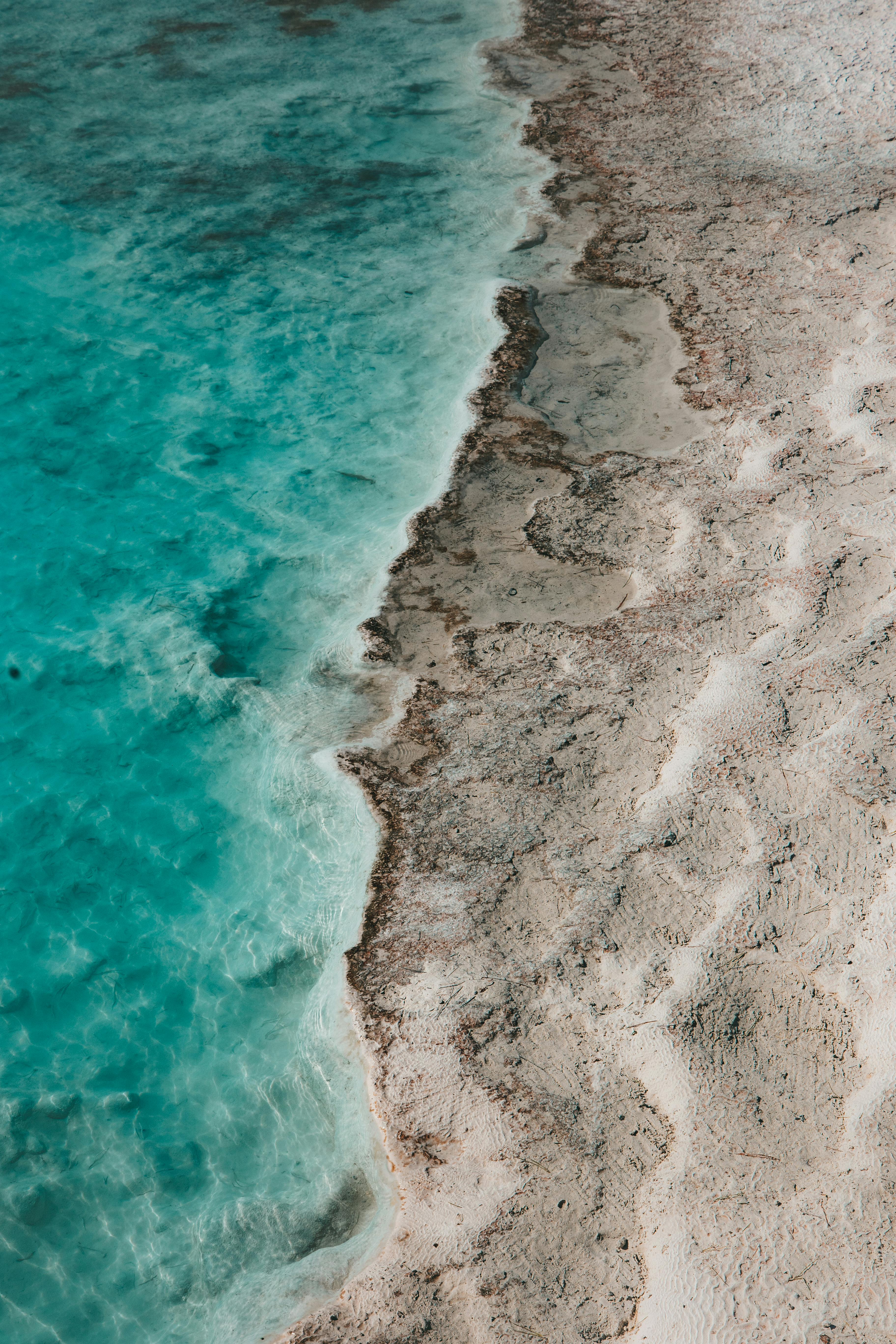 A stunning aerial shot capturing the turquoise sea meeting sandy beach shores.
