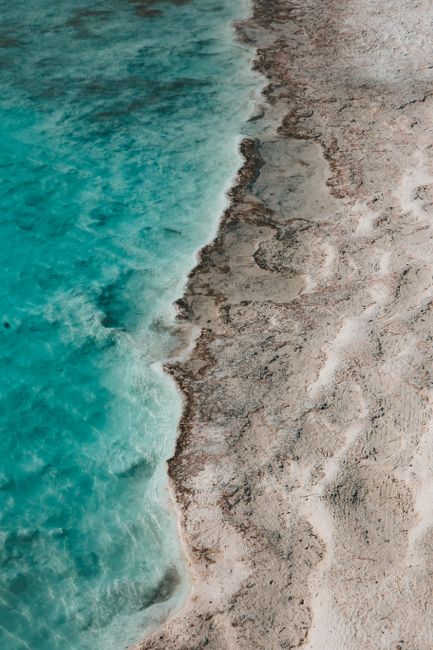 A stunning aerial shot capturing the turquoise sea meeting sandy beach shores.