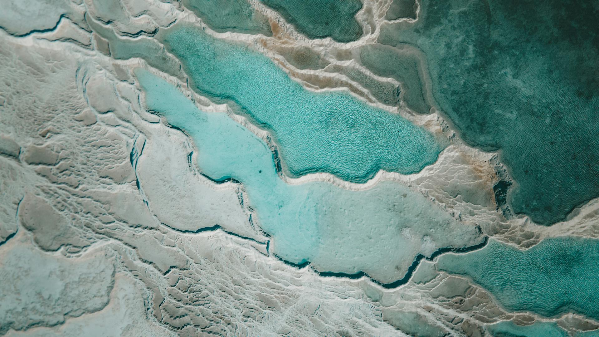 Stunning aerial capture of natural turquoise thermal pools with marbled textures.