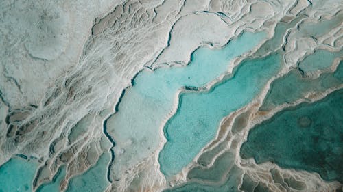 Aerial Shot of Heaps of Icy Snow on a Glacier and Turquoise Melted Ice 