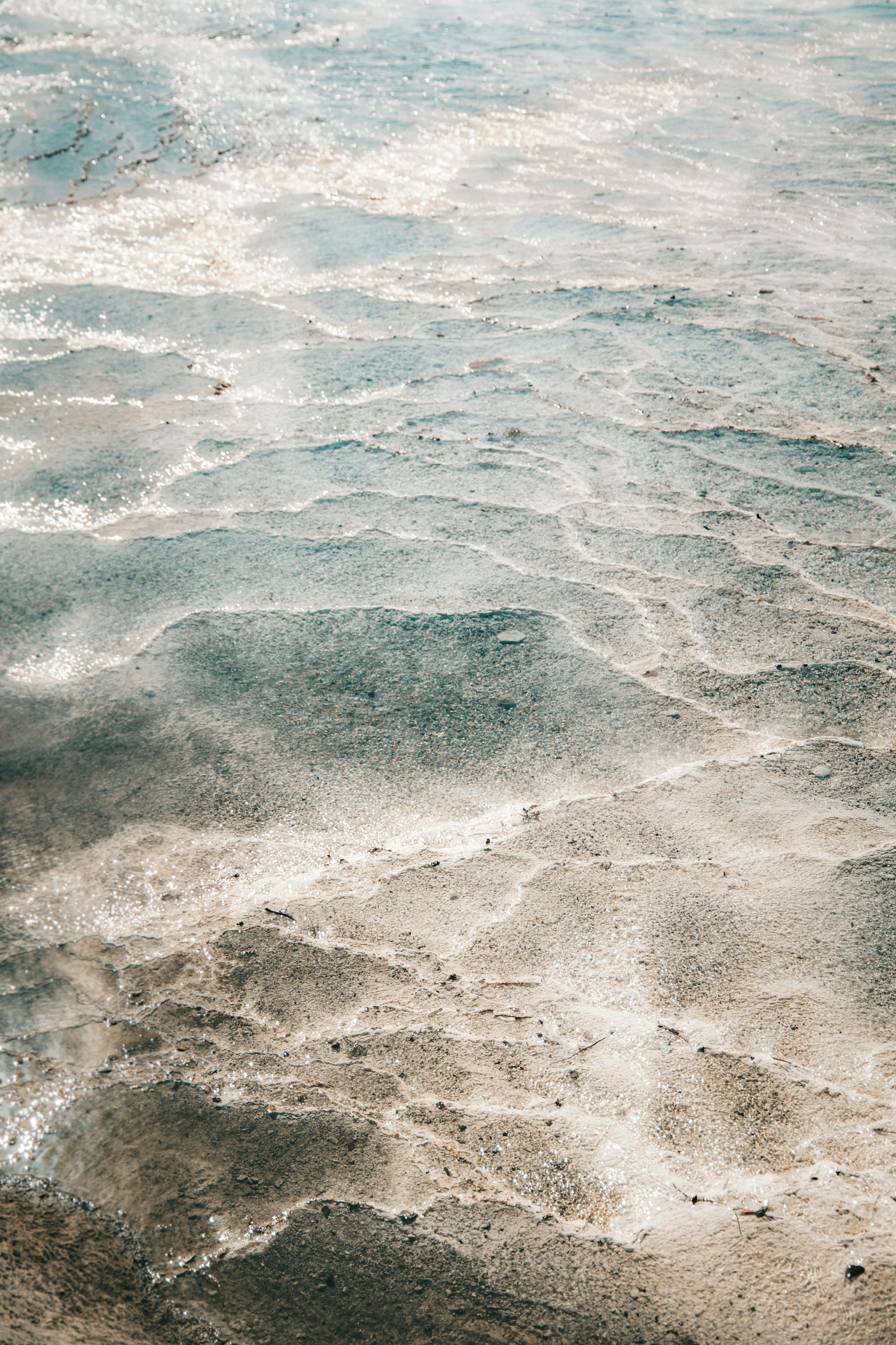 沙滩上波光粼粼的水面特写镜头，捕捉光线反射和纹理