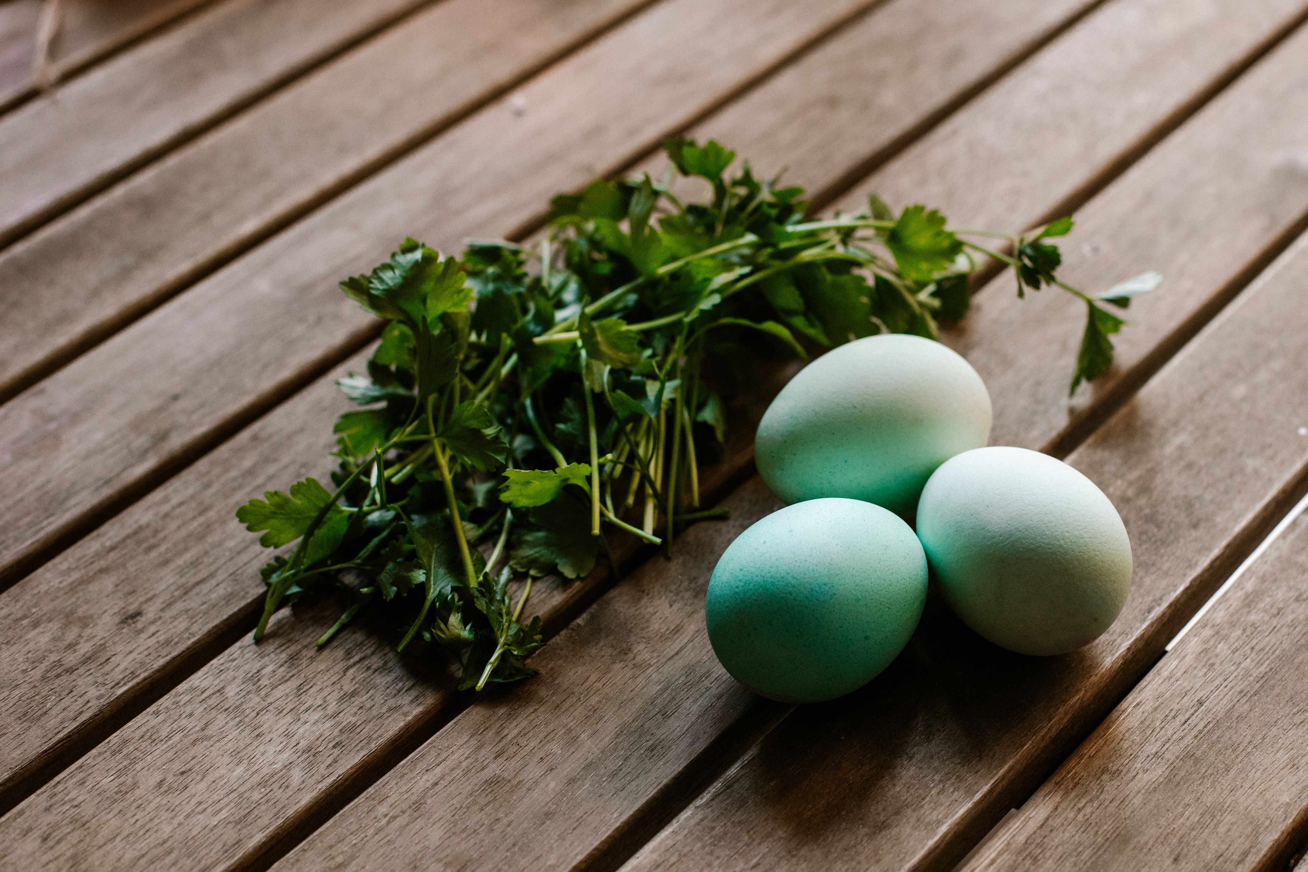 Spinach, kale and eggs — natural food sources of lutein and zeaxanthin — arranged on a wooden table