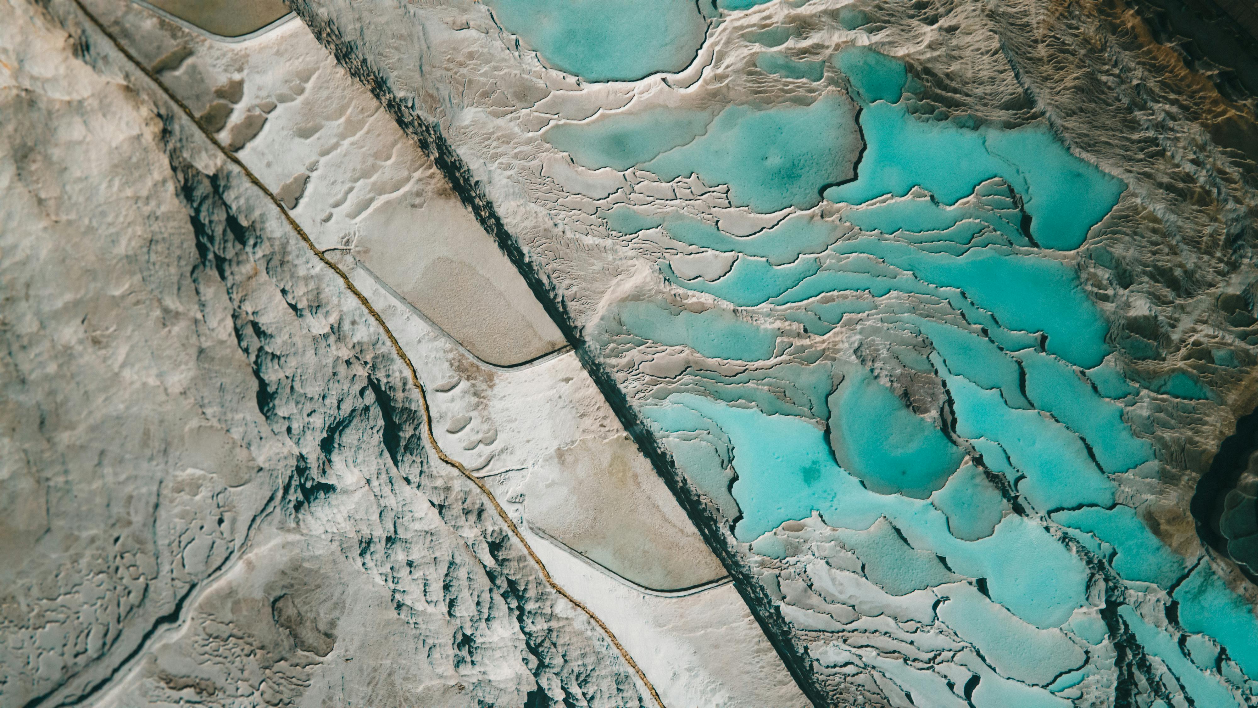 Aerial photo showcasing vibrant blue geothermal hot springs and surrounding mud flats.