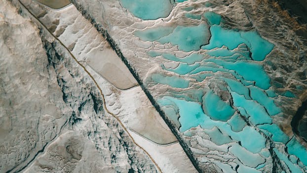 Aerial photo showcasing vibrant blue geothermal hot springs and surrounding mud flats.