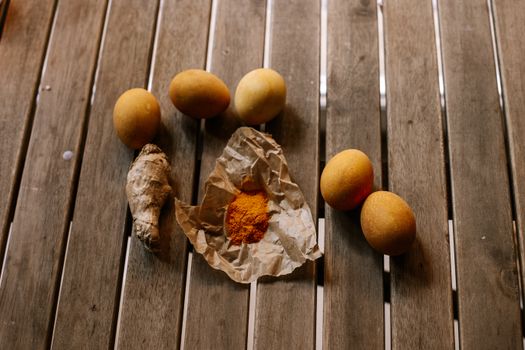 Top view of eggs, ginger root, and turmeric on rustic wooden table.