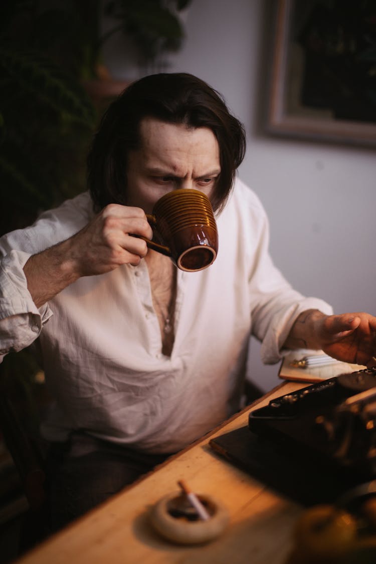 Man Writing On Typewriter And Drinking Coffee