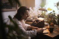 Woman in White Long Sleeve Shirt Sitting by the Table