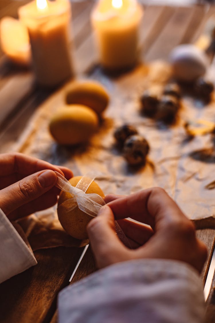 Hands Tying Ribbon Around Egg