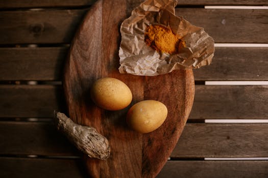 Top view of brown eggs, ginger, and spices on a wooden board.