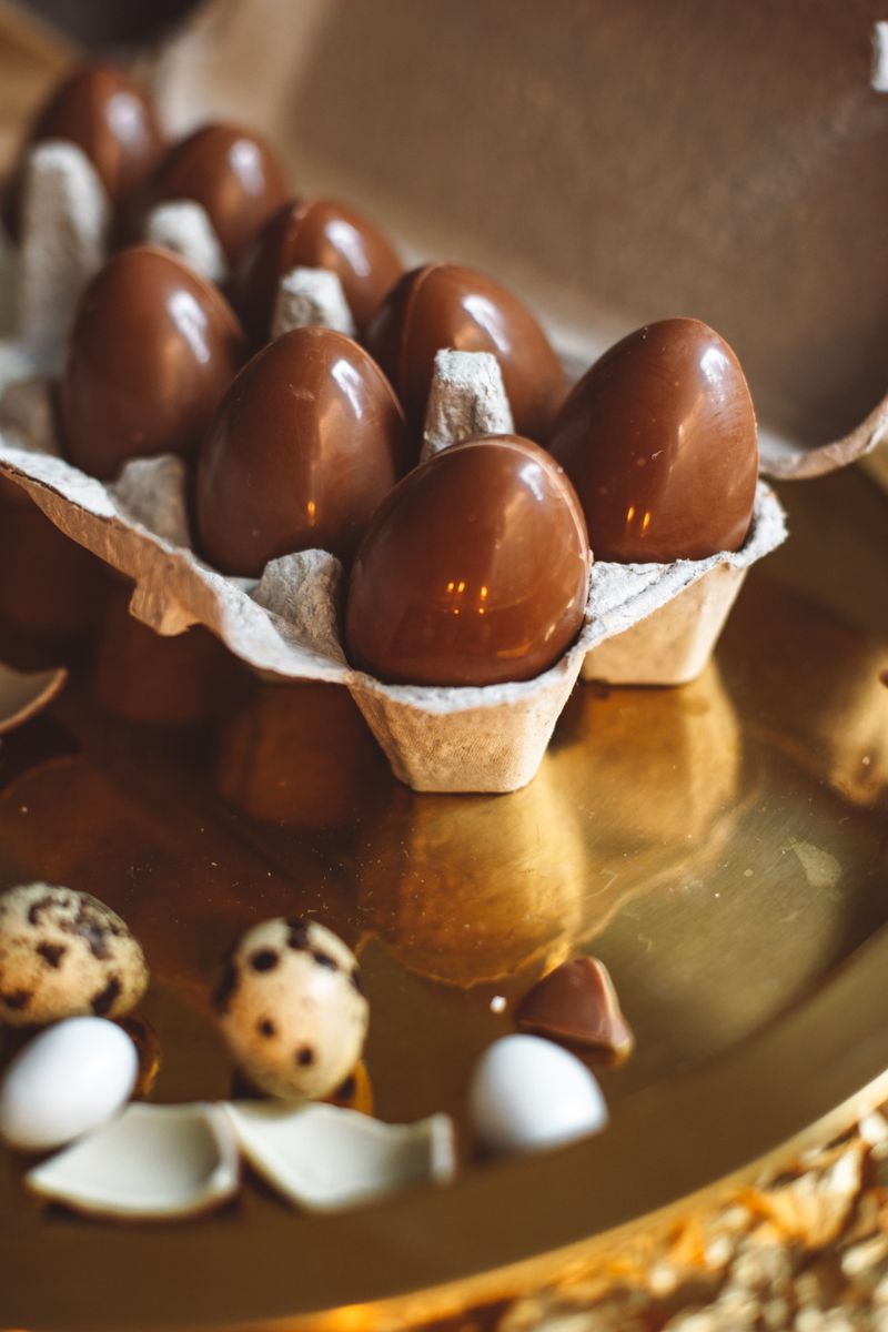 Close-up of chocolate eggs in a carton on a reflective surface.