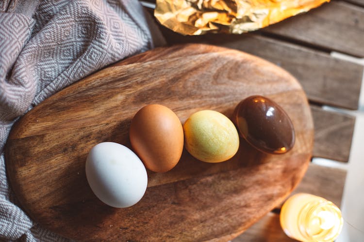 Variously Colored Eggs Lying On Wooden Board