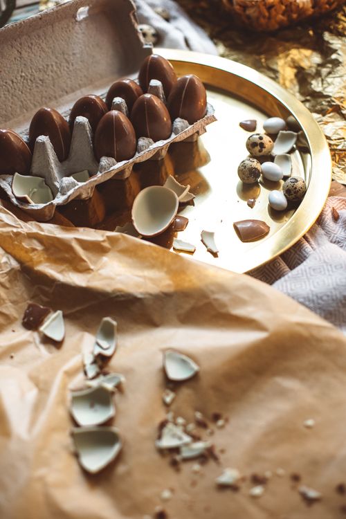 Free An artistic display of chocolate eggs and quail eggs in a carton with cracked shells on brown paper. Stock Photo