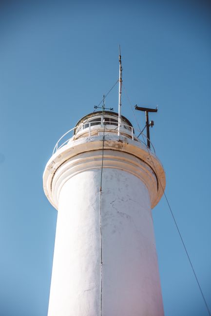 A low-angle view of a lighthouse tower set against a vivid blue sky, showcasing its striking architecture.