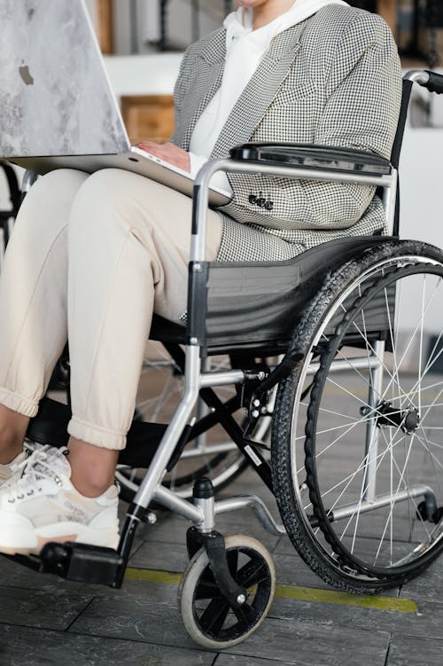 Crop woman in wheelchair typing on laptop