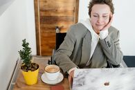 Cheerful woman in wheelchair working on laptop in cafe
