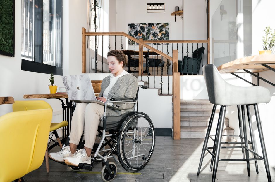 Mujer trabajando de forma remota en un laptop en un café moderno y accesible.