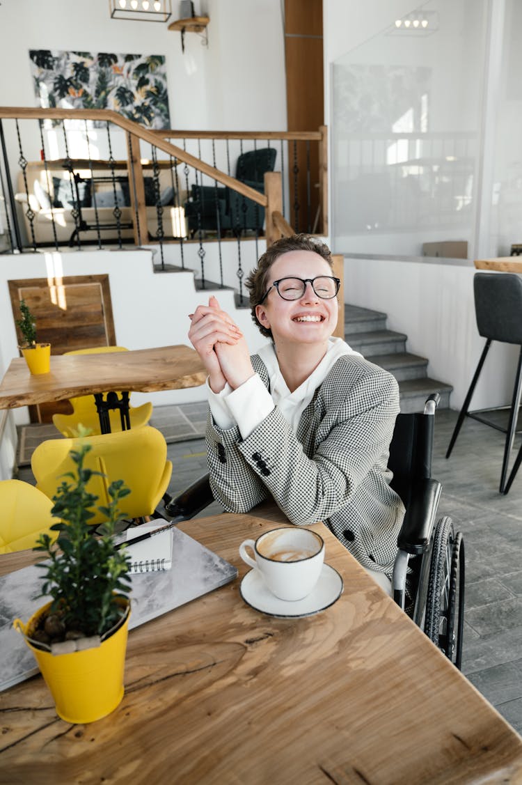 Satisfied Woman In Wheelchair Having Latte In Coffee Shop