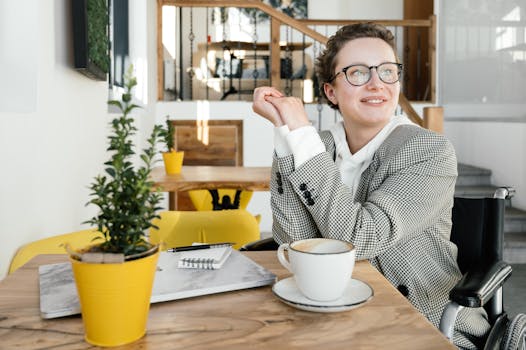 A woman in a wheelchair enjoys a coffee break at a bright and welcoming café.