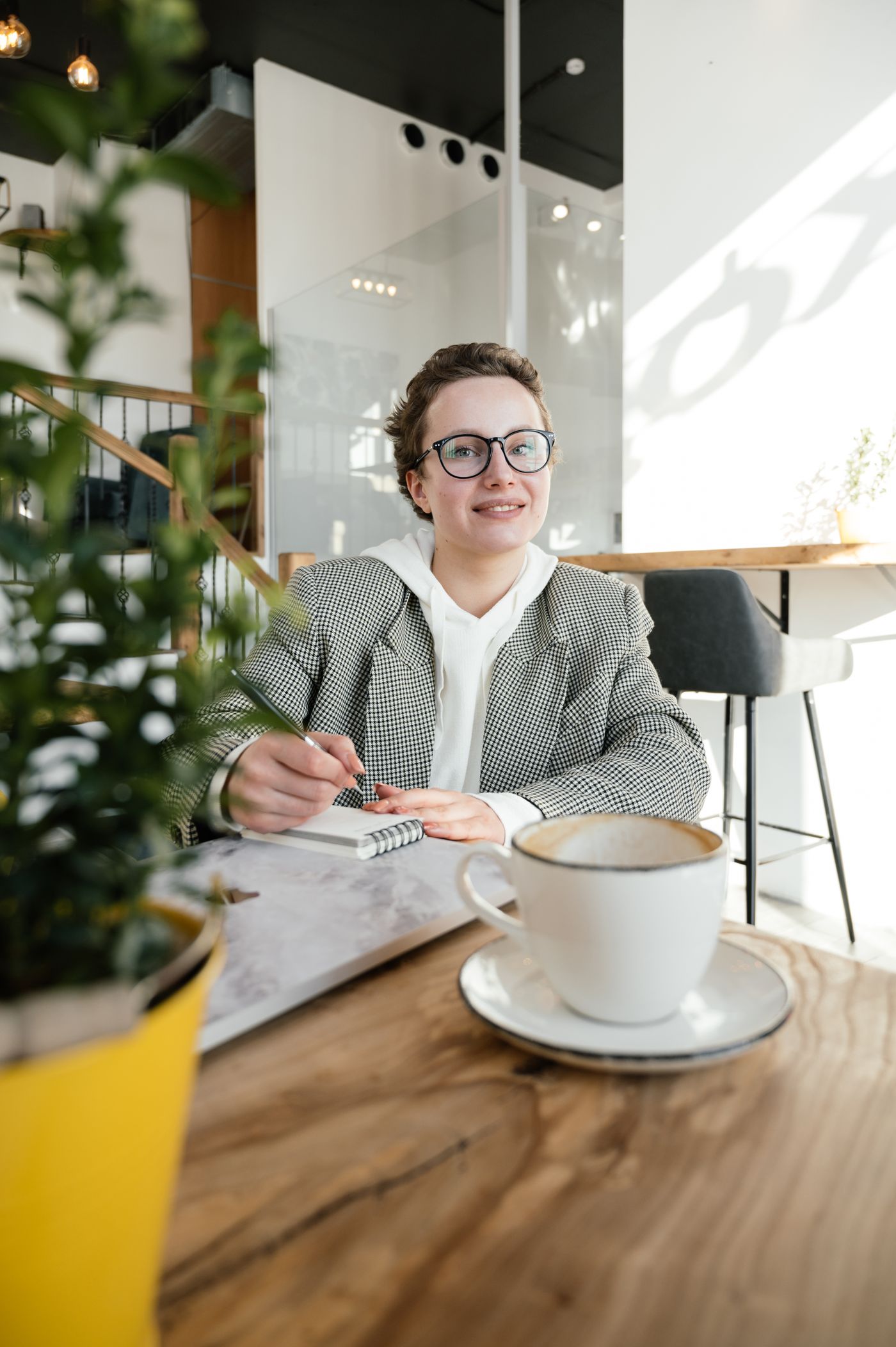 A smiling professional planning her next steps with a notebook in a sunlit cafe