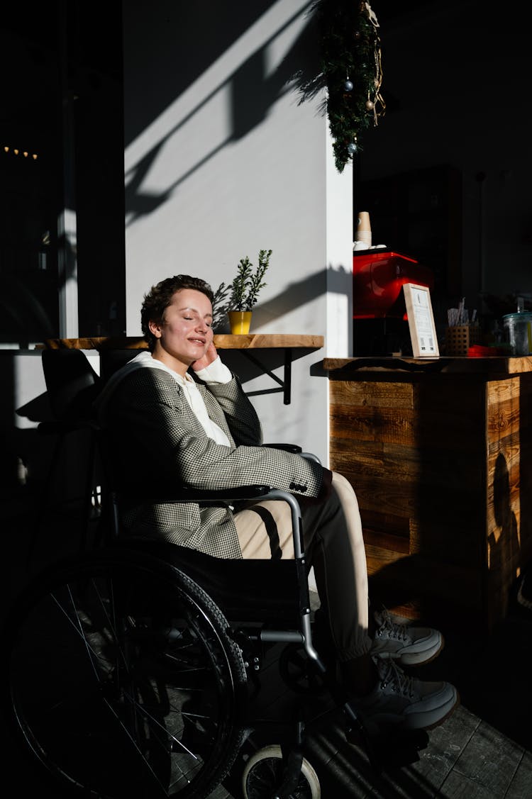 Glad Woman In Wheelchair Sitting In Light Room