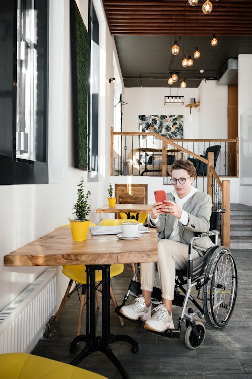Focused woman in wheelchair browsing smartphone in cafe