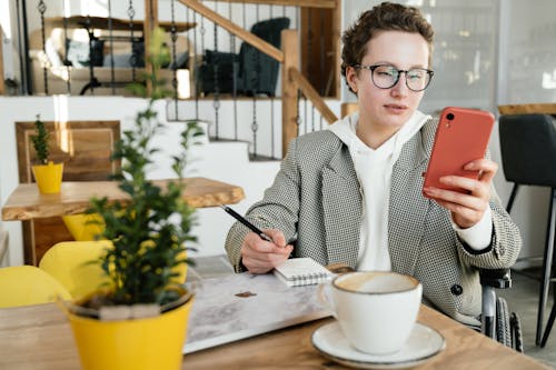 Focused businesswoman in wheelchair using smartphone in cafe