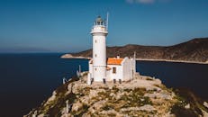 风景如画的白色灯塔坐落在岩石海岸线上，俯瞰深蓝色的大海