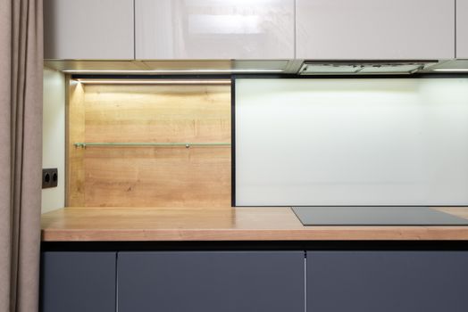 Cook top built in wooden table under cupboard with hood in modern light house kitchen