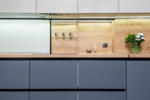 Contemporary kitchen with cupboards above floral bouquet in vase and decorative mugs on shelf at home