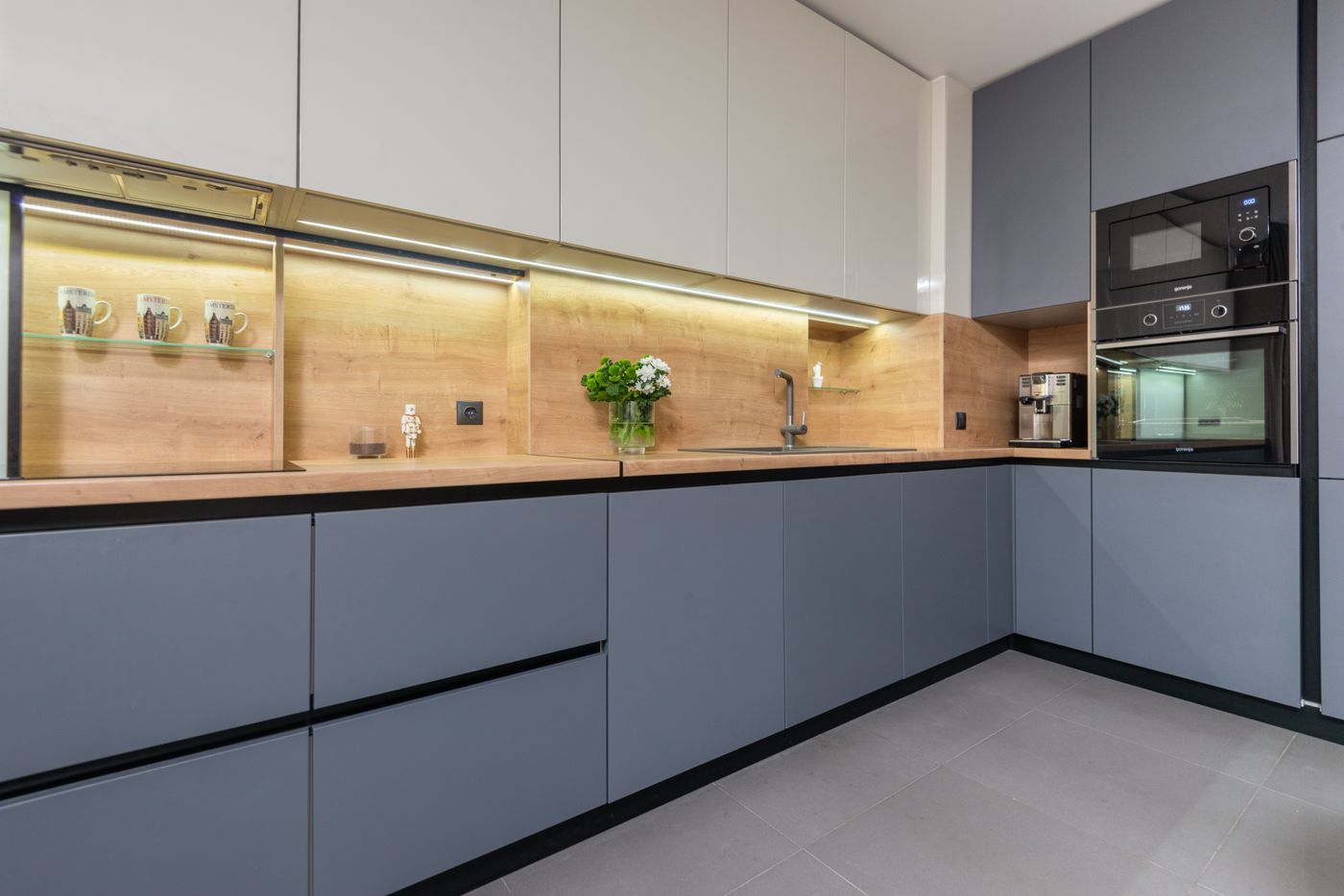 Handleless grey modular kitchen with integrated appliances and under-cabinet lighting