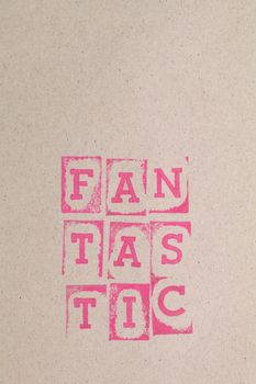 Vertical shot of 'FANTASTIC' pink stamped text on cardboard, ideal for design projects with copy space.
