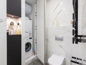 Bathroom interior with washing machine against toilet bowl