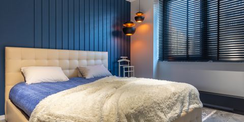 A bed made up with a soft cream fleece blanket over a blue comforter in a calm bedroom
