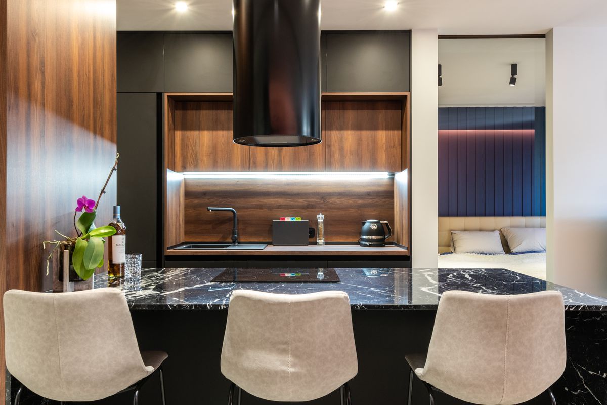 A kitchen with dark cabinets and a black island