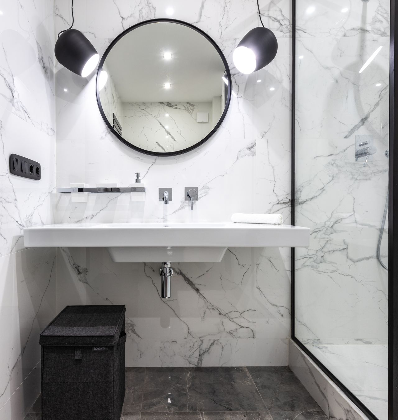 floating-modern-bathroom-vanity White floating bathroom vanity with round mirror in a marble bathroom