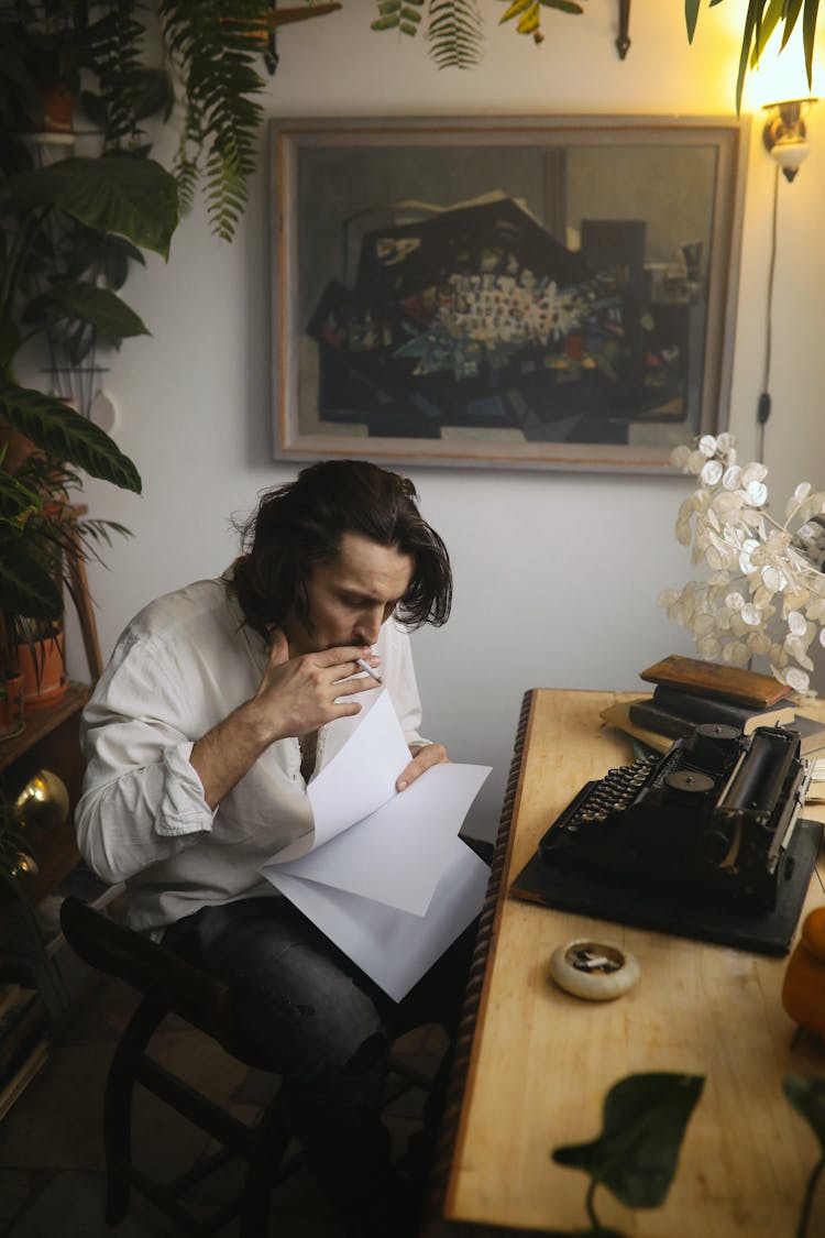 A Man Smoking Holding Sheets Of Paper