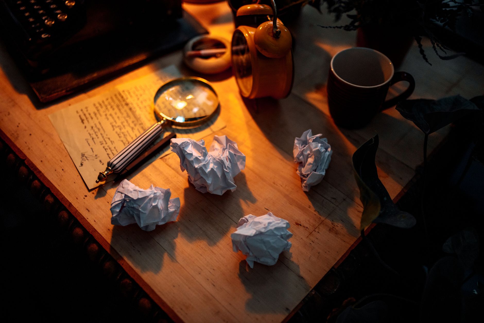A cluttered writer's desk with papers, pens, and a computer