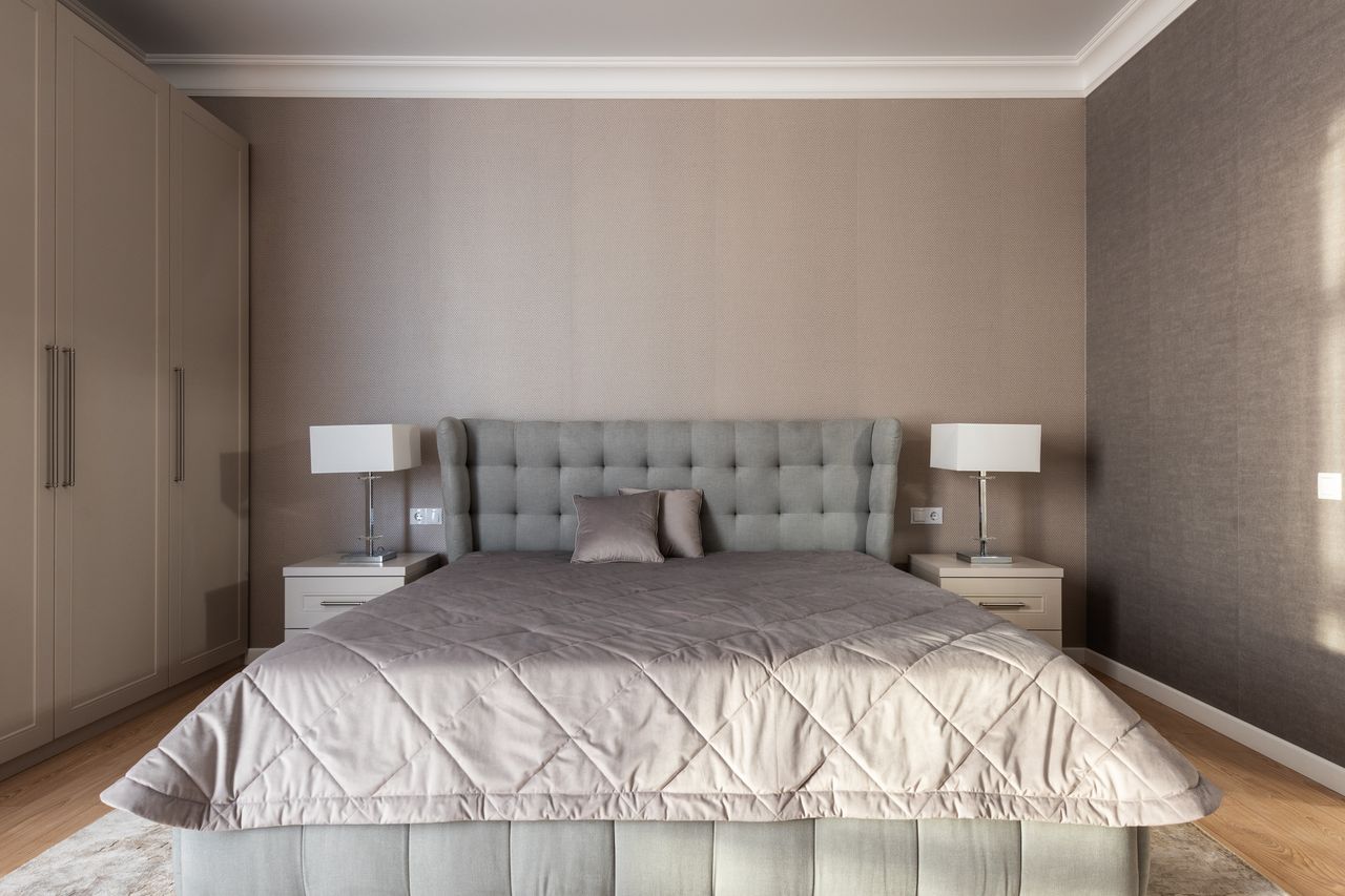 Gray bedroom with matching bedside tables and lamps on both sides of the bed