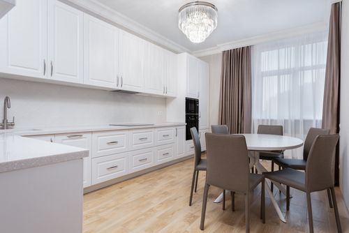 Free White cabinets against round shaped table with chairs on parquet under shiny lamp in house Stock Photo