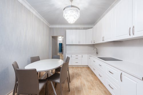 Contemporary kitchen interior with table against cupboards in house