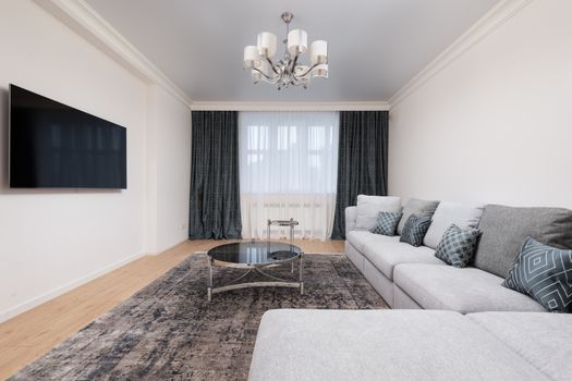 Contemporary living room with decorative cushions on sofa against table and TV with black screen in house