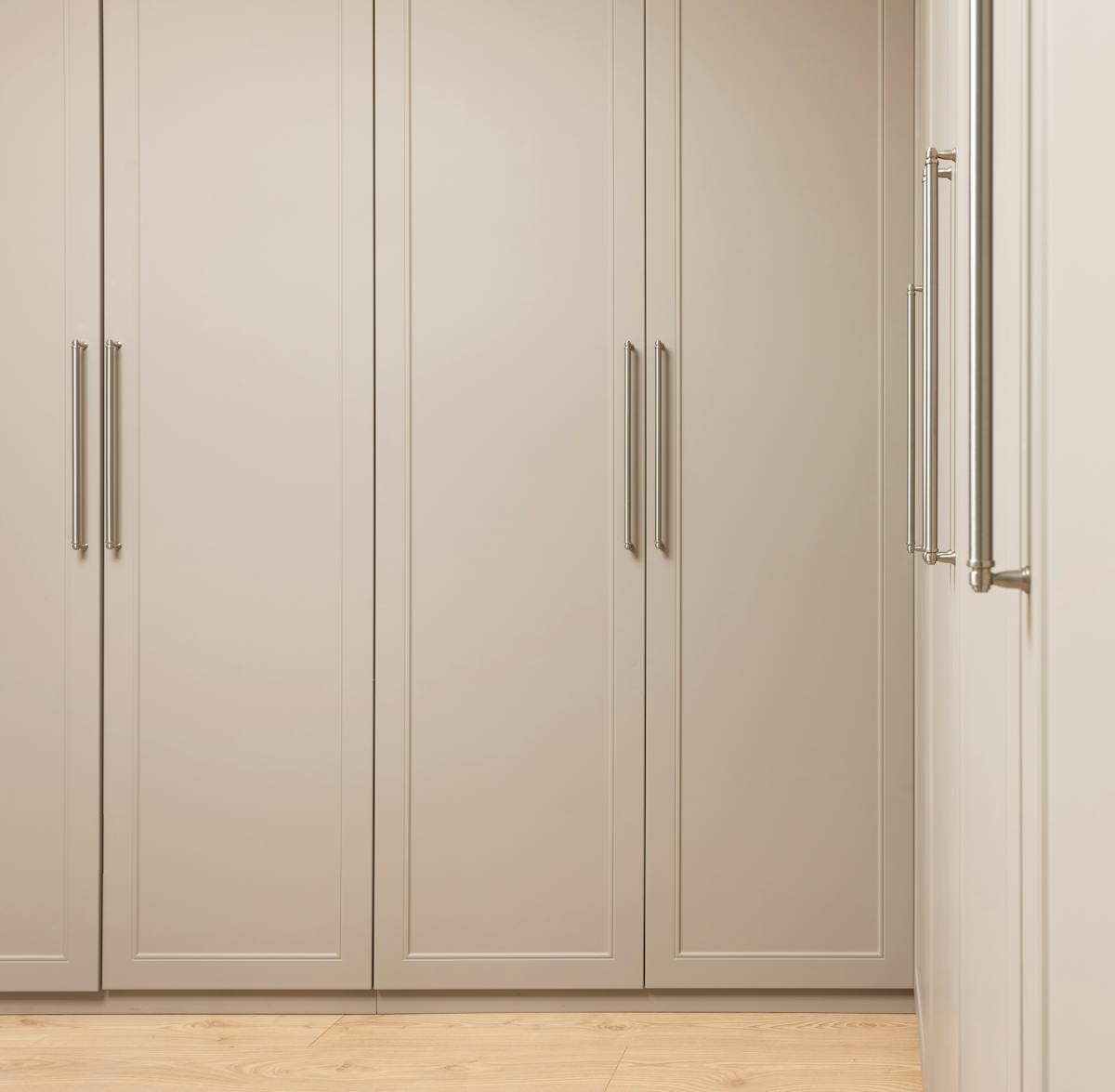 Contemporary closet with beige doors and metal handles above floor in modern light house