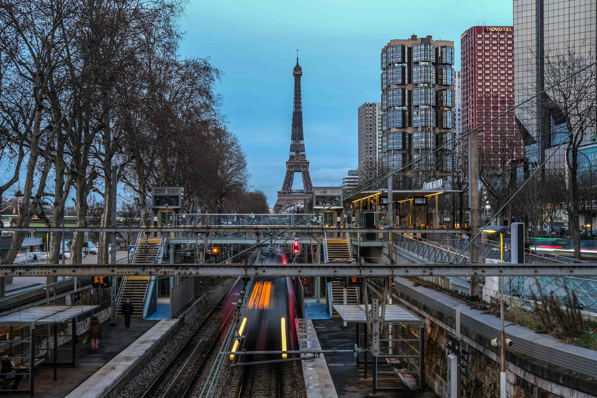 View of the Eiffel Tower from a Paris metro station during daytime with city buildings and transport below.