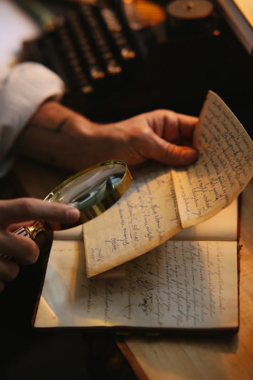 Free A Person Reading a handwritten Letter with a Magnifying Glass Stock Photo