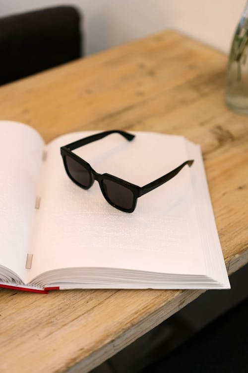 Black Framed Sunglasses on White Book Page