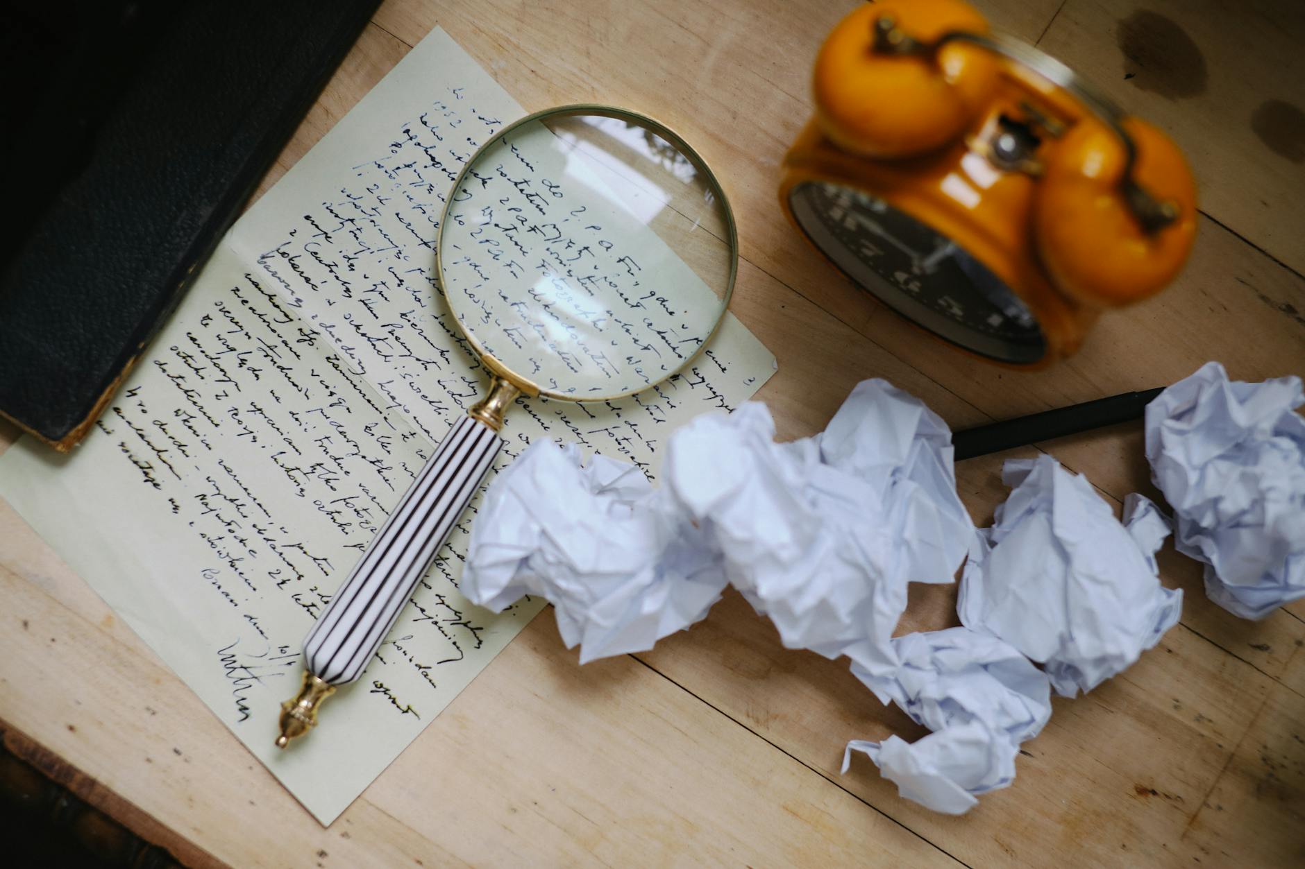 A vintage scene featuring a magnifying glass on a handwritten letter, crumpled papers, and an old clock.
